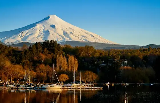 Volcán nevado sobre un lago al atardecer de otoño